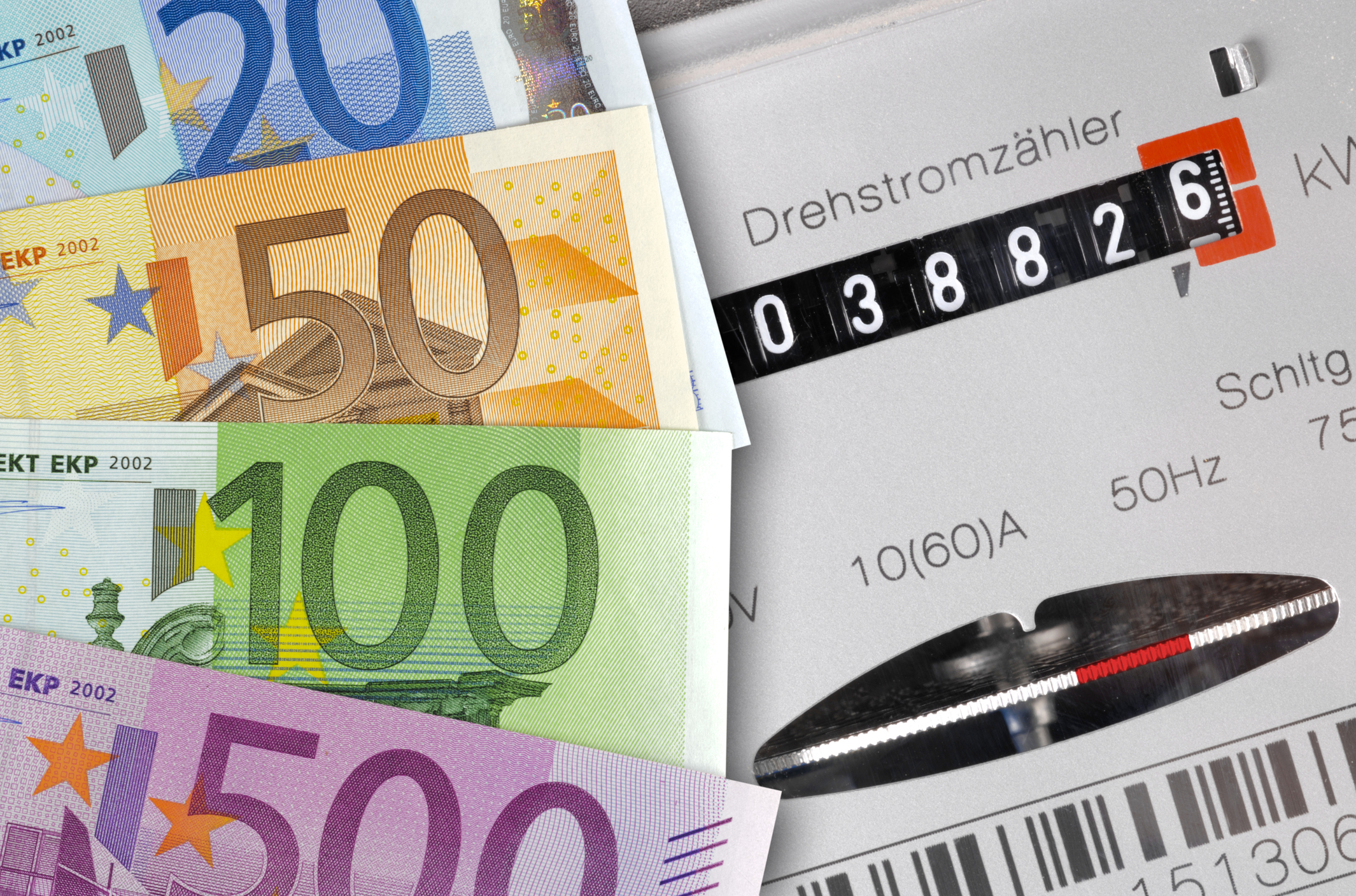 Nahaufnahme eines analogen Stromzählers mit Euroscheinen, symbolisch für die explodierenden Stromkosten und die finanzielle Belastung durch Netzentgelte im Mehrfamilienhaus.