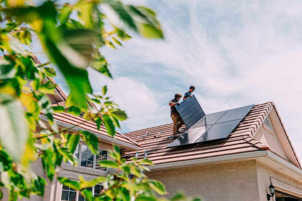 Handwerker bei der Dachmontage einer Solaranlage zur dezentralen Stromerzeugung.
